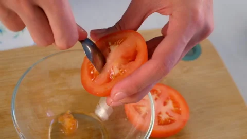 Chef cooking removing tomato seeds deseeding vegetable half over glass bowl Video stock 312465860