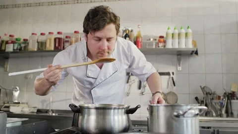 Chef is cooking in a restaurant kitchen. Handsome man cooks soup in the kitchen. Stock Footage 131457678