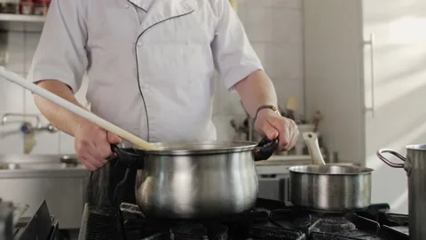 Chef is cooking in a restaurant kitchen. Handsome man cooks soup in the kitchen. Stock Footage 131457713