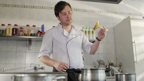 Chef is cooking in a restaurant kitchen. Handsome man cooks soup in the kitchen. Stock Footage 131457975
