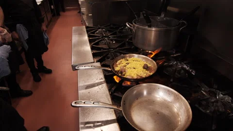 Chef cooking in a restaurant kitchen over a gas stove large flames Stock Footage 274107579