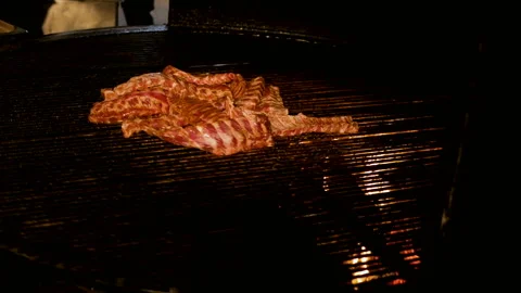 Chef cooking ribs on grill. appetizing pork ribs rotate on cast iron grill Stock Footage 94368002