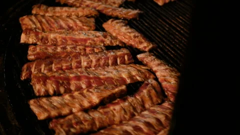 Chef cooking ribs on grill. appetizing pork ribs rotate on cast iron grill Stock Footage 94369000