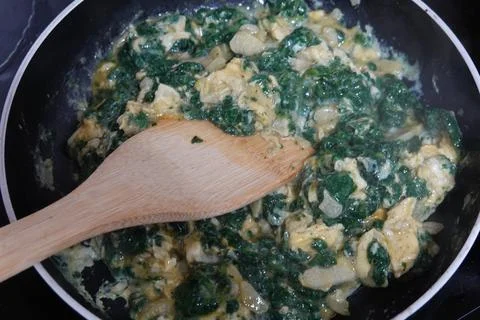 Chef cooking scrambled eggs with nettles in a pan Stock Photos
