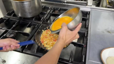 Chef cooking scrambled eggs with vegetables on a stove Stock Footage 344100144