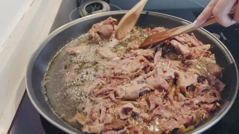Chef cooking shredded duck confit with herbs and spices in a hot frying pan with Stock Footage 344401863
