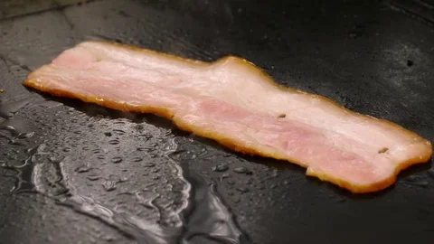 Chef cooking slice of bacon, flips over by iron spatula Stock Footage 76952447