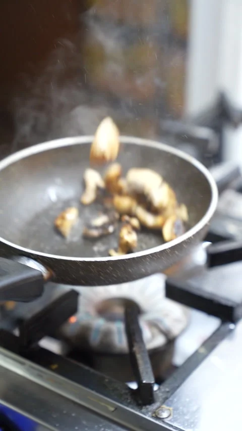 Chef cooking sliced mushrooms in pan at restaurant kitchen Stock Footage 340406583