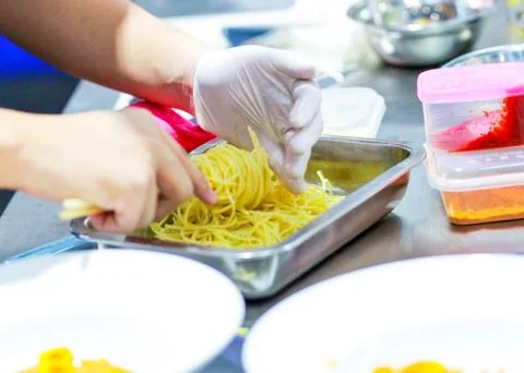 Chef cooking spaghetti in the kitchen, Chef putting Spaghetti to the plate Stock Photos