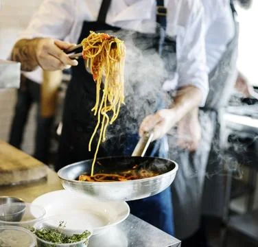 Chef cooking spaghetti in the kitchen Stock Photos