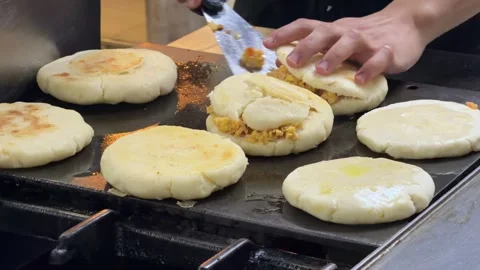 Chef cooking stuffed arepas on a griddle in a restaurant kitchen 스톡 동영상 344100199