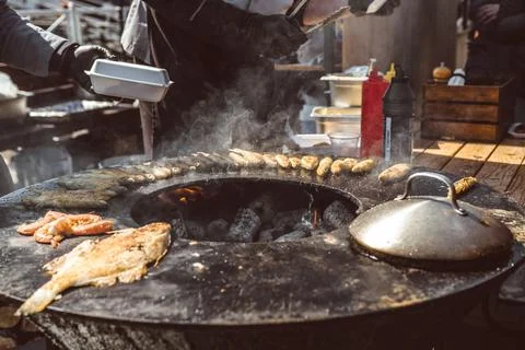 Chef cooking various fresh fish on a round charcoal grill in an outdoor mar.. Stock Photos