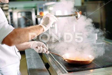 Chef cooking vegetables in wok pan. Shallow dof. Stock Photos