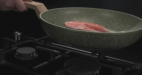 Chef cooks fish steak in frying pan over black background. Cooking in restaurant Stock Footage 250791822