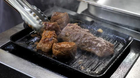 A chef cooks meat in a frying pan. raw meat in a hot frying pan or on a grill. Stock Footage 336626668