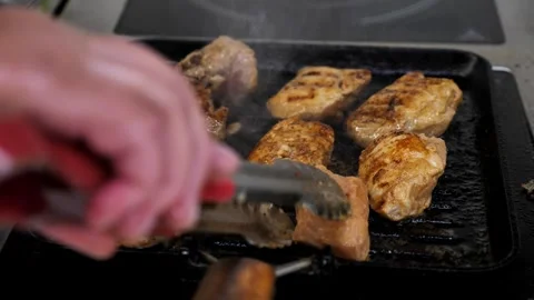 A chef cooks meat in a frying pan. raw meat in a hot frying pan or on a grill. Stock Footage 336626674