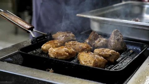 A chef cooks meat in a frying pan. raw meat in a hot frying pan or on a grill. Stock Footage 336626765