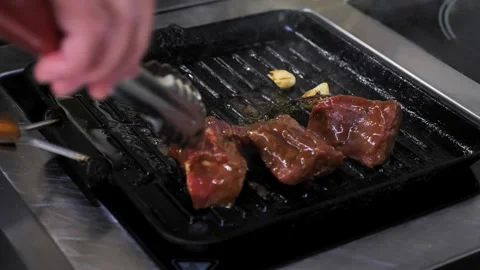 A chef cooks meat in a frying pan.  meat in a hot frying pan or on a grill. Stock Footage 337594092