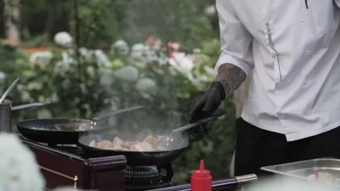 Chef cooks meat on an open fire in a burning pan outdoors in slow motion Video stock 142186144