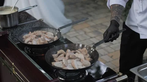 Chef cooks meat on an open fire in a burning pan outdoors in slow motion Stock Footage 142799305