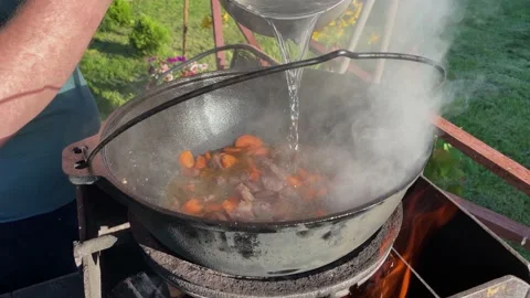 Chef cooks pilaf in a large cauldron on an open fire Stock Footage 200843016