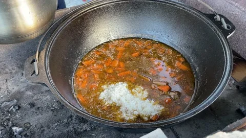 Chef cooks pilaf in a large cauldron on an open fire Stock Footage 200843023