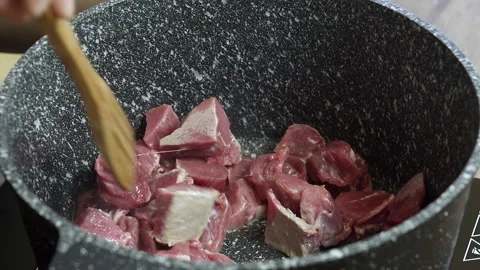 A chef cooks raw beef in a black pot, close up Stock Footage 135415301