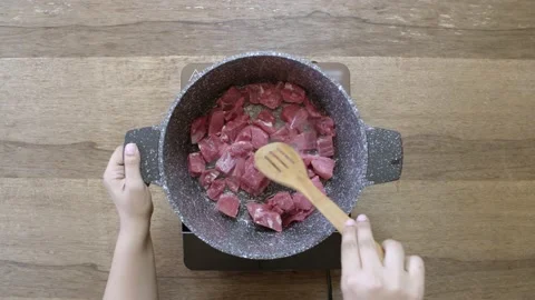 A chef cooks raw beef in a black pot, top view Video stock 135427024
