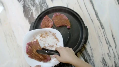 Chef cooks raw beef steak in a large pan Stock Footage 135540197