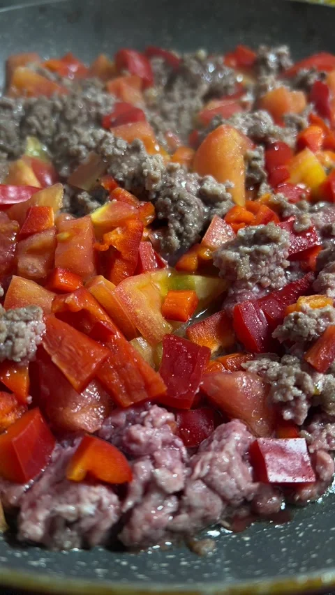 Chef cooks raw minced beef, red bell pepper and tomatoes in frying pan Stock Footage 304764504