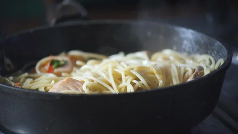 Chef cooks spaghetti pasta in a pan with fried salmon in a restaurant kitchen. Stock-Footage 124710261