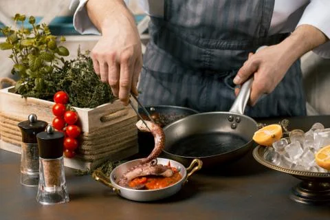 Chef cooks spreadsheets octopus tentacles. Chef lays octopus on tomato sauce. Stock Photos