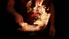 Vegetables fry on a large frying pan on fire. Cooking at the festival. Girl  chef pouring vegetables into disposable utensils. Stock Photo