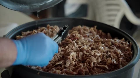 Chef covering a large pot of hot pulled pork or shawarma with a lid Stock Footage 314286563