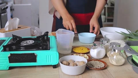 Chef cracking and beating egg with fork in blue bowl surrounded by kitchen Vidéo 341487468