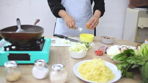 Chef cracking an egg into small yellow bowl while preparing meal in kitchen Stock Footage 341487464