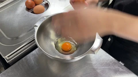 Chef cracking fresh brown eggs into a stainless steel bowl 스톡 동영상 344100104