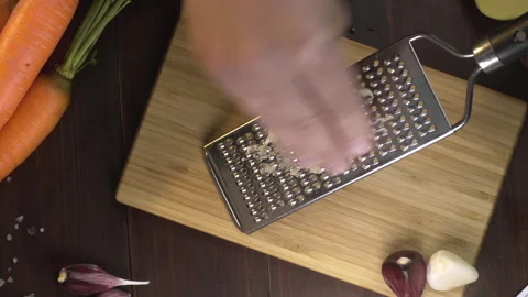 Chef crates garlic on the small grater on the wooden board Video stock 143777027