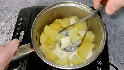 The chef crushes boiled potatoes, butter and milk with a pusher Stock Footage 230015441