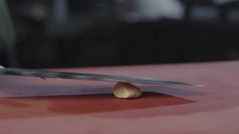 The chef crushes the garlic with a large, buzzing knife. Stock Footage 230705076