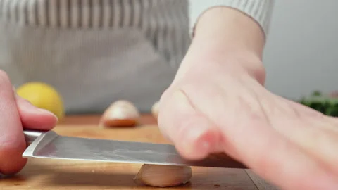 Chef crushing garlic close-up and squeeze with a side knife in 4K. Stock Footage 145997984