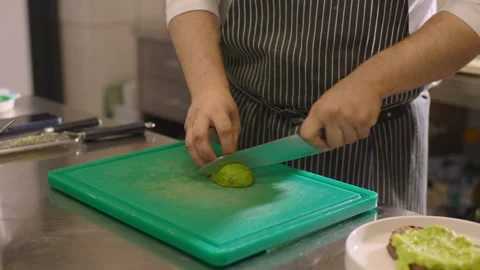 A chef cuts an avocado in a restaurant kitchen. Video stock 277131531