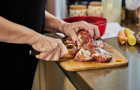 Chef cuts the beef with knife and prepares it for baking in the oven Stock Photos
