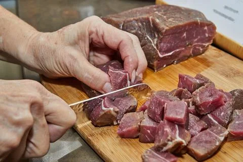 Chef cuts the beef meat into cubes for cooking Stock Photos