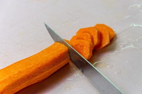 The chef cuts a carrot with a knife Stock Photos