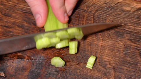 Chef cuts celery vegetable on wooden cut board. Stock Footage 253276704