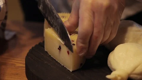 A chef cuts cheese on a black cutting board. Video stock 129522492
