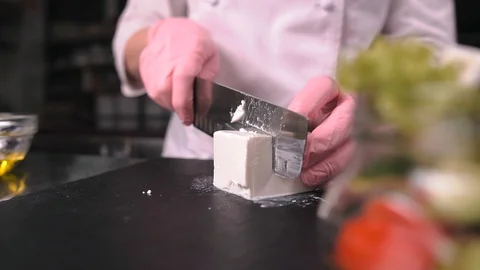 Chef cuts the cheese with a knife in slow motion Video stock 124160437
