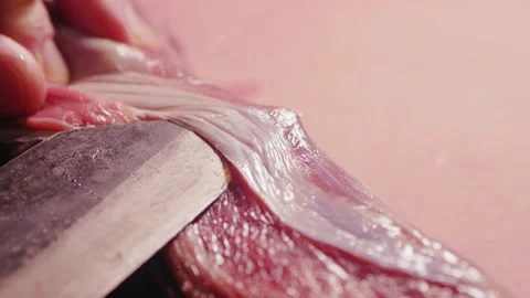 Chef cuts off connective tissue and surface membrane from a raw beef tenderloin Stock Footage 203913115