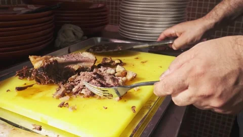 The chef cuts the cooked meat with a knife on a cutting board and puts it on a Stock Footage 255932172